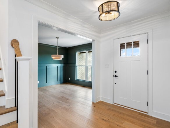 Bright entryway with white walls, wooden flooring, and a modern ceiling light.