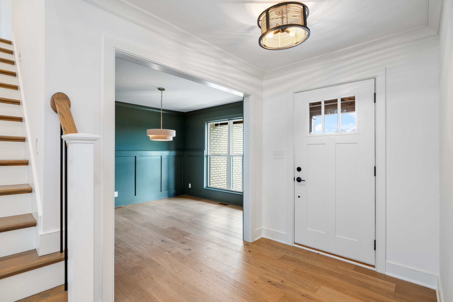 Bright entryway with white walls, wooden flooring, and a modern ceiling light.