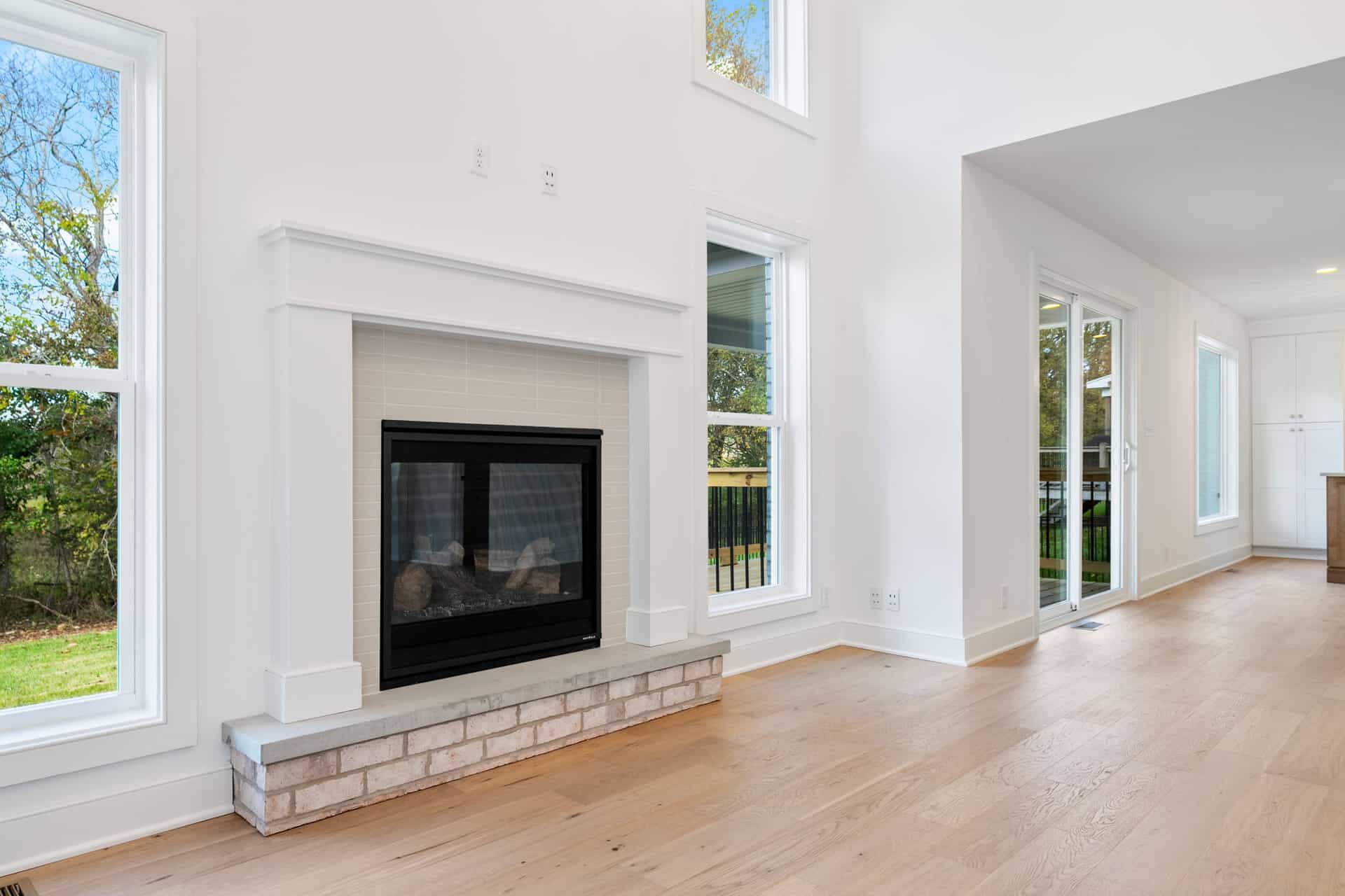 Bright living room with fireplace, large windows, and hardwood floors.