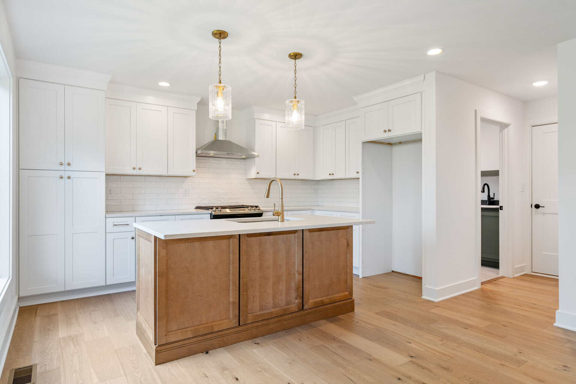 Modern kitchen with white cabinets, wooden island, and pendant lighting.