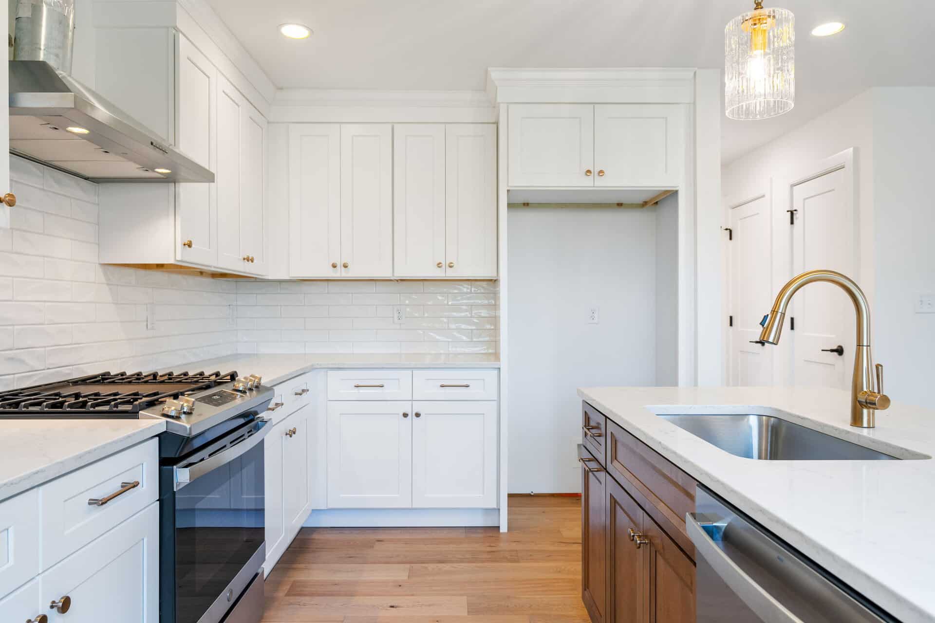Modern kitchen with white cabinets, gold fixtures, and a wooden island.