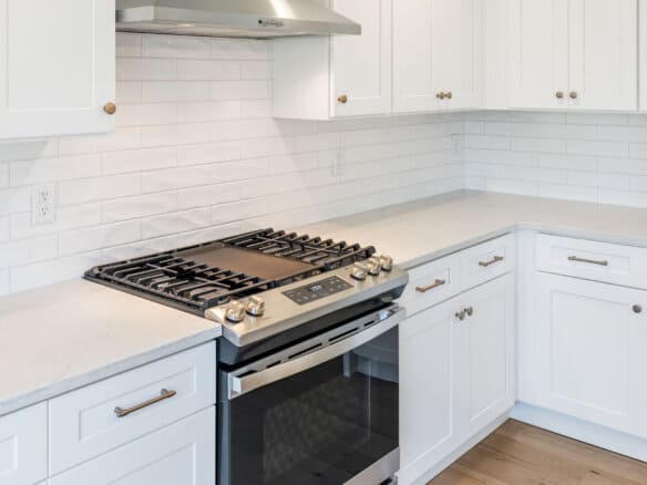 Modern white kitchen with gas stove and subway tile backsplash.