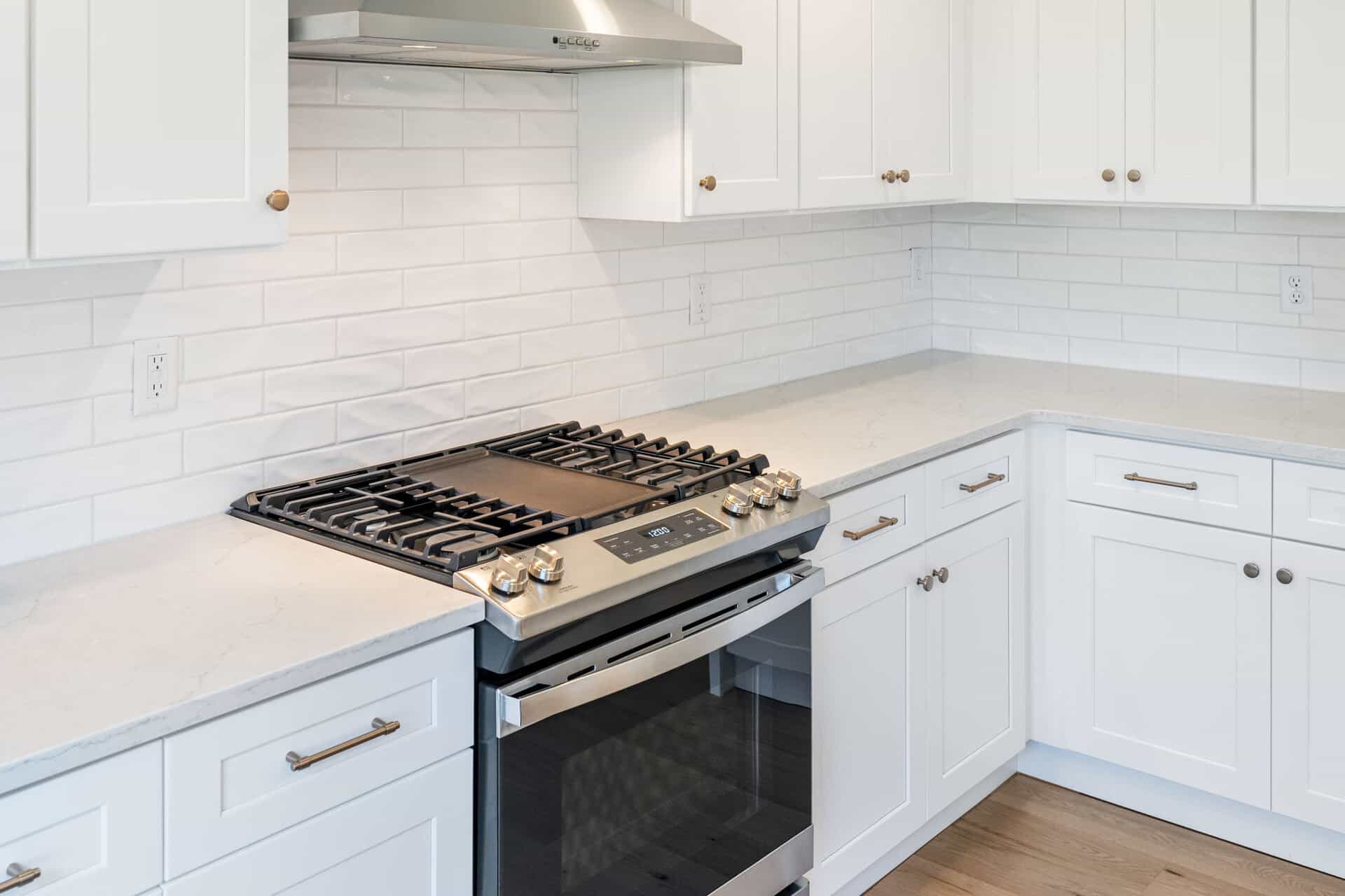 Modern white kitchen with gas stove and subway tile backsplash.