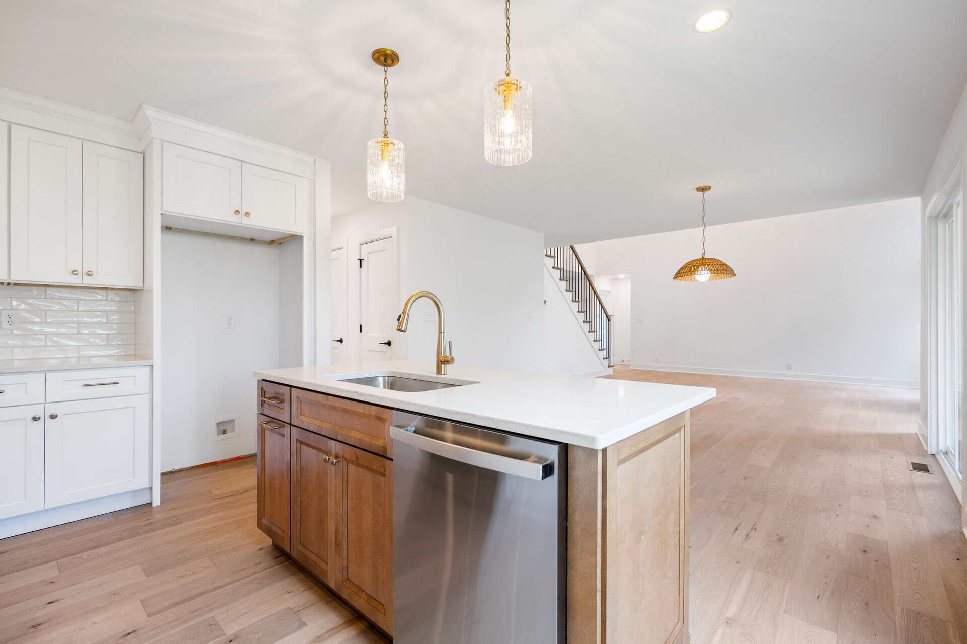 Modern kitchen with white cabinets, island, and pendant lighting in a new home.