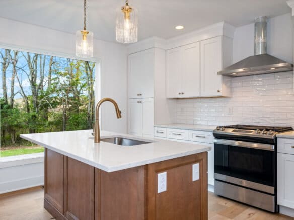 Modern kitchen with white cabinets, stainless steel stove, and island with pendant lights.