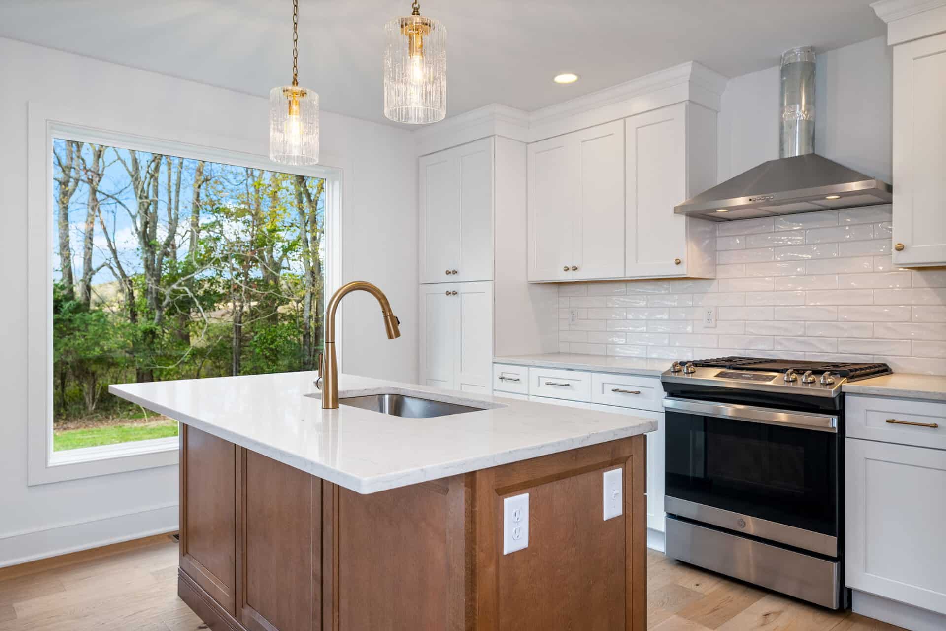 Modern kitchen with white cabinets, stainless steel stove, and island with pendant lights.