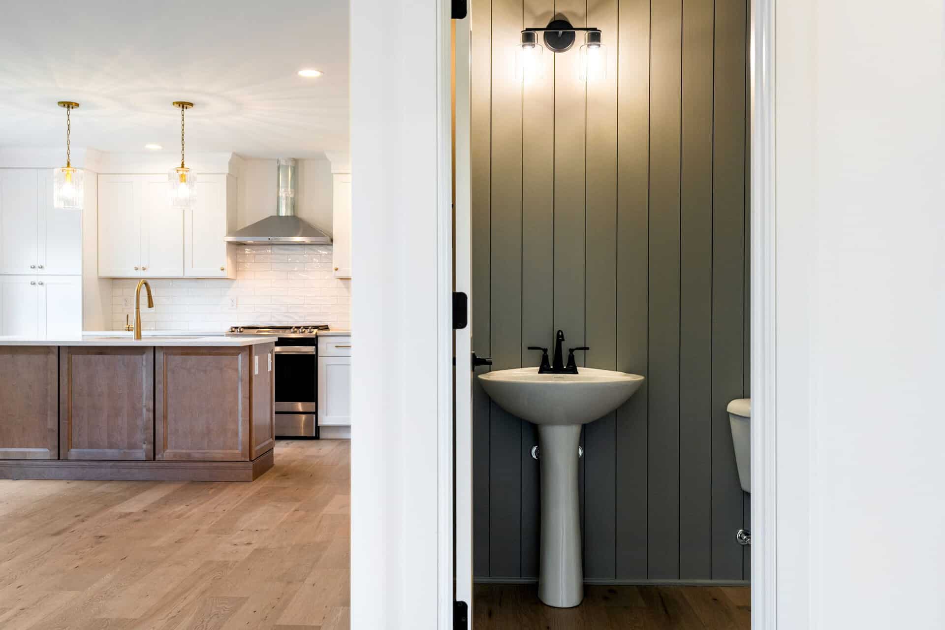 Modern kitchen with white cabinets and a small bathroom with a pedestal sink.