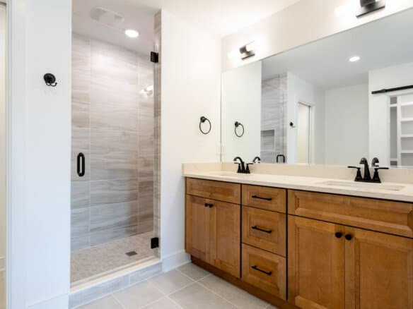 Modern bathroom with double vanity and walk-in shower in a new home.