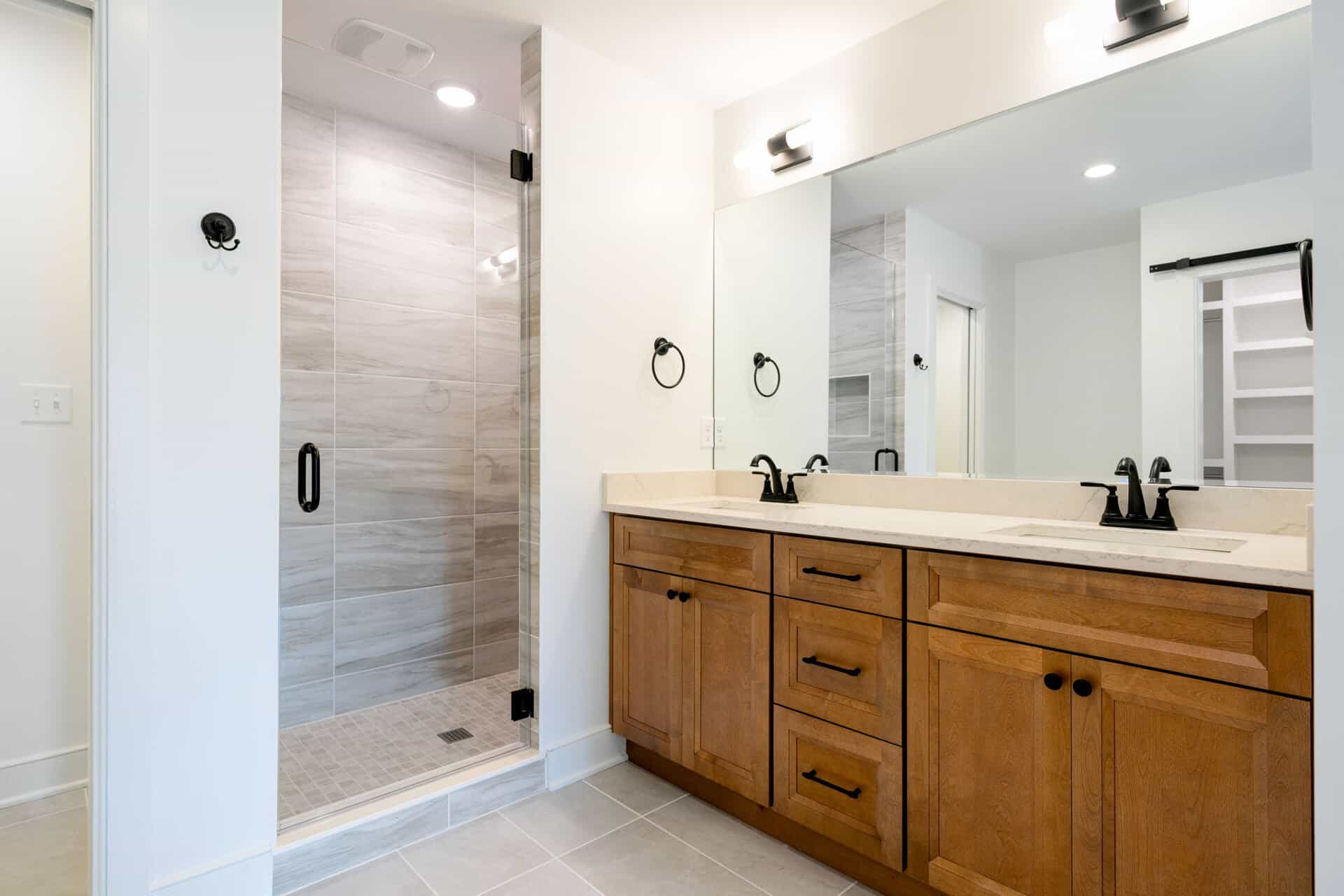 Modern bathroom with double vanity and walk-in shower in a new home.