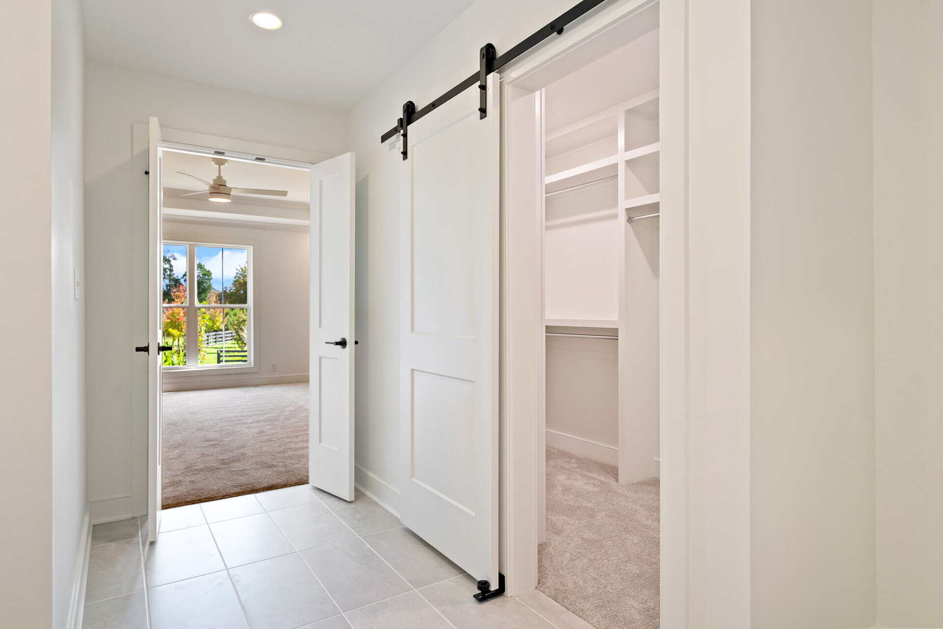 Bright hallway with sliding barn door leading to closet and adjacent room.