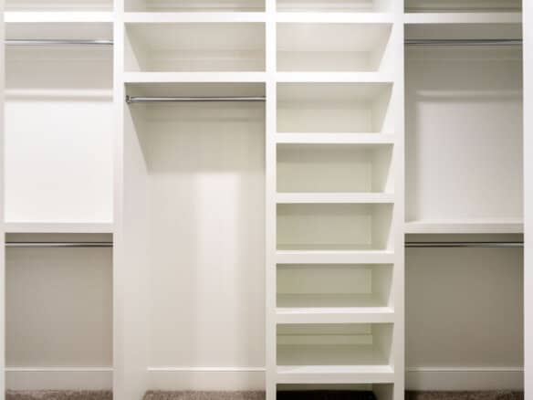 Empty white walk-in closet with shelves and hanging rods.