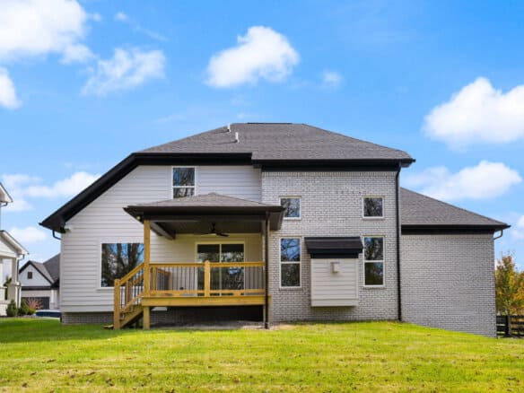 Modern two-story house with a wooden deck and gray brick exterior.
