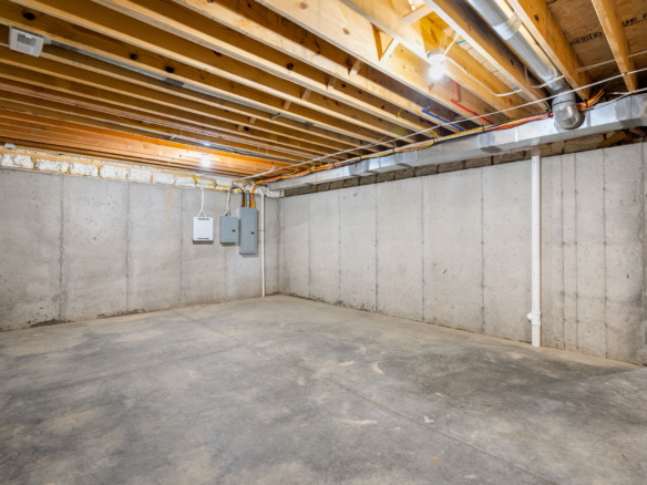 unfinished basement with concrete walls, exposed joists, and visible wiring along the ceiling