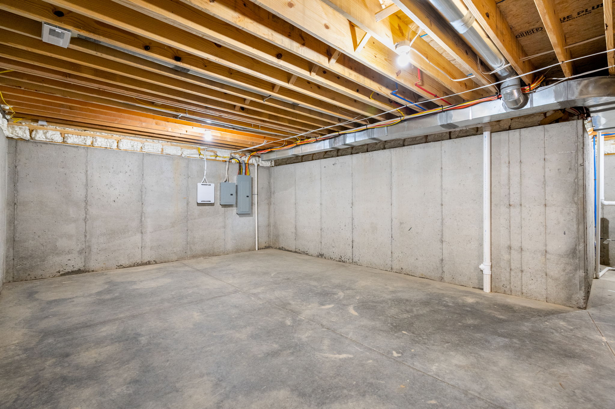 unfinished basement with concrete walls, exposed joists, and visible wiring along the ceiling