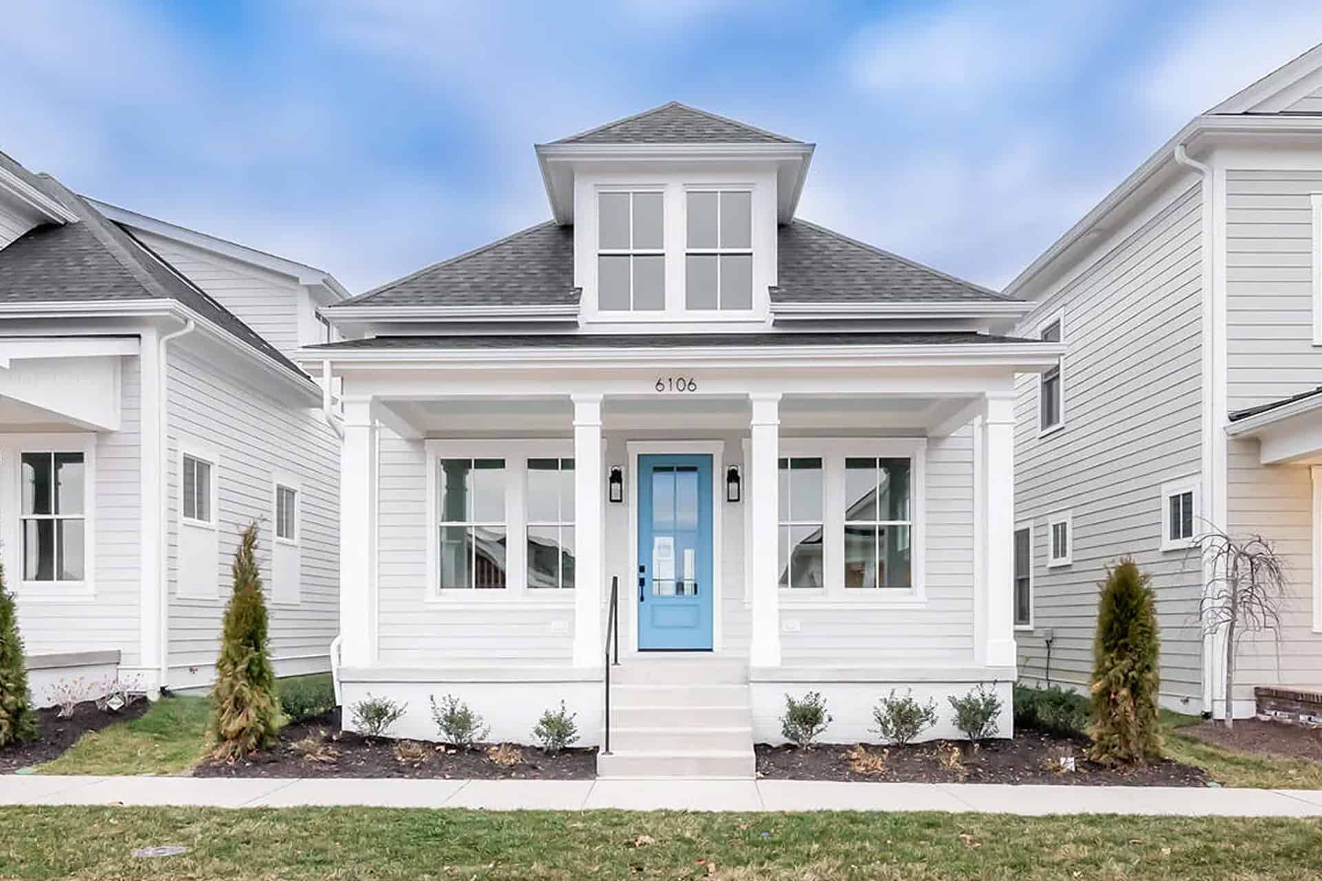 White modern house with blue front door and small front yard.