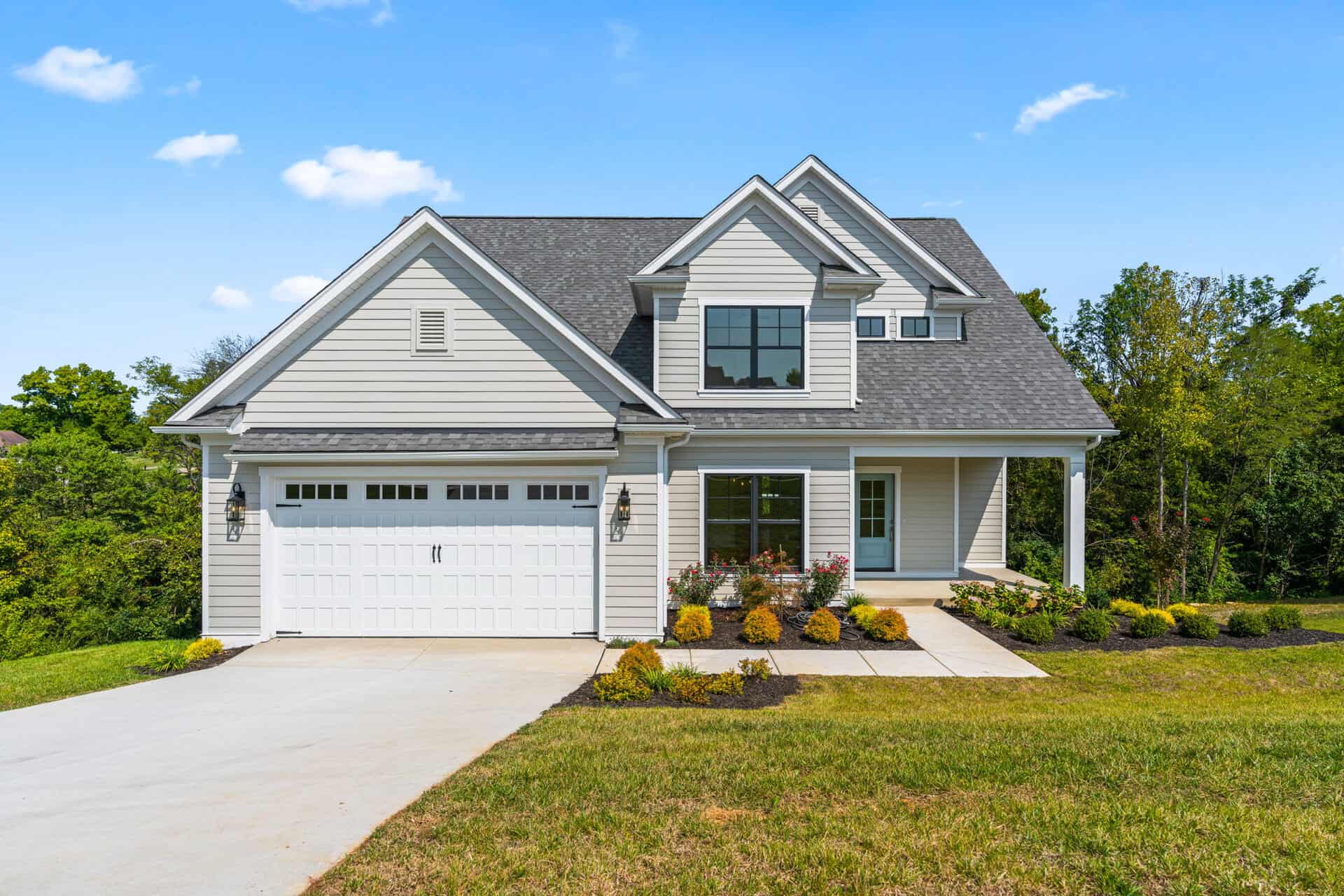 Modern two-story home with white siding, black window frames, and a front porch.