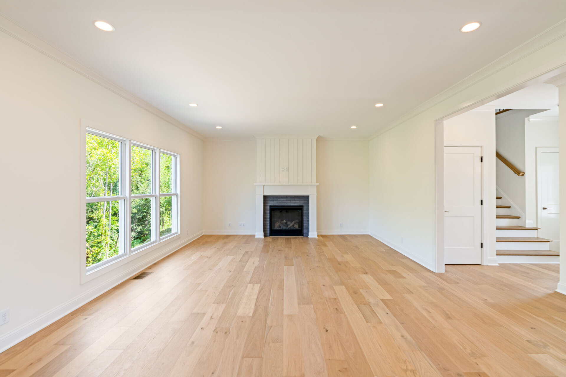 Bright living room with large windows, white walls, and hardwood floors.