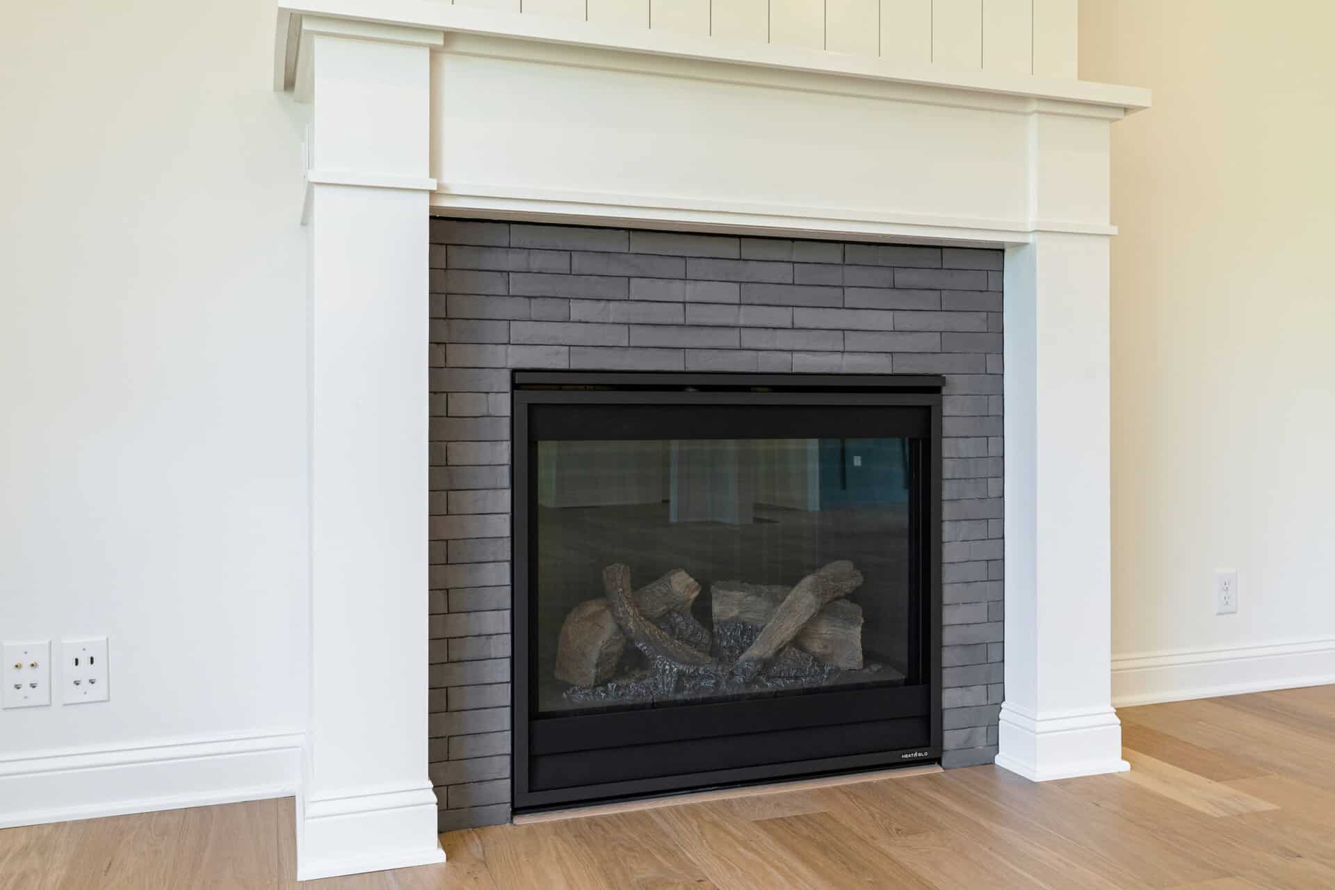 Modern fireplace with black frame and gray brick surround in a living room.