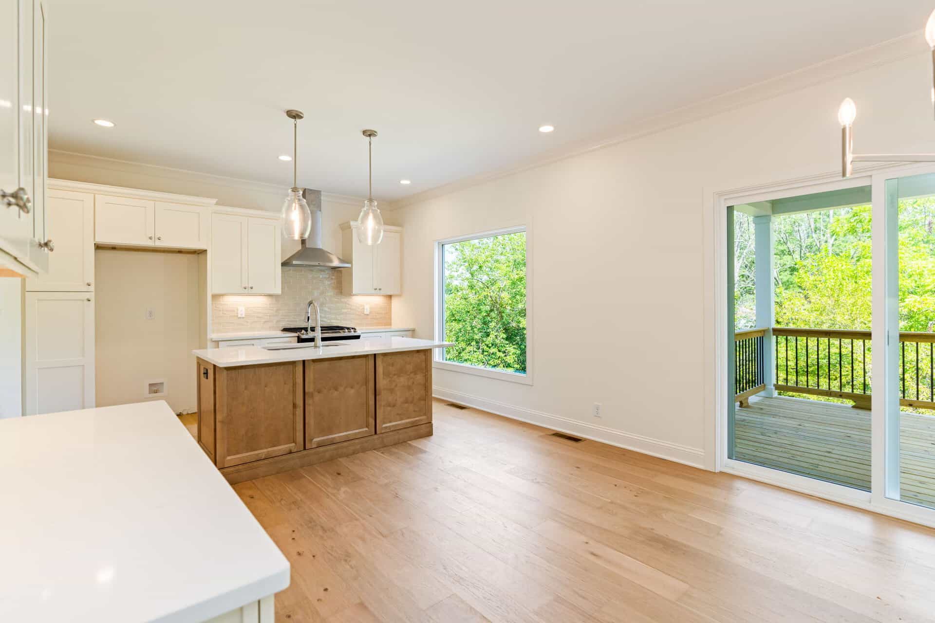Bright open kitchen and dining area with large windows and sliding door to deck.