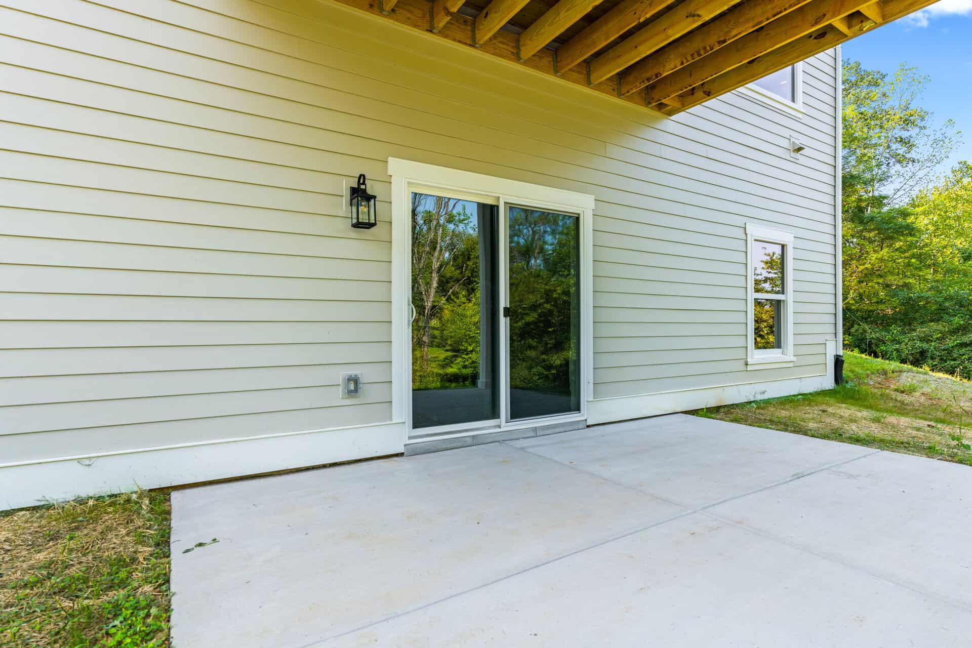 Back patio with sliding glass door and exterior wall of a modern home.