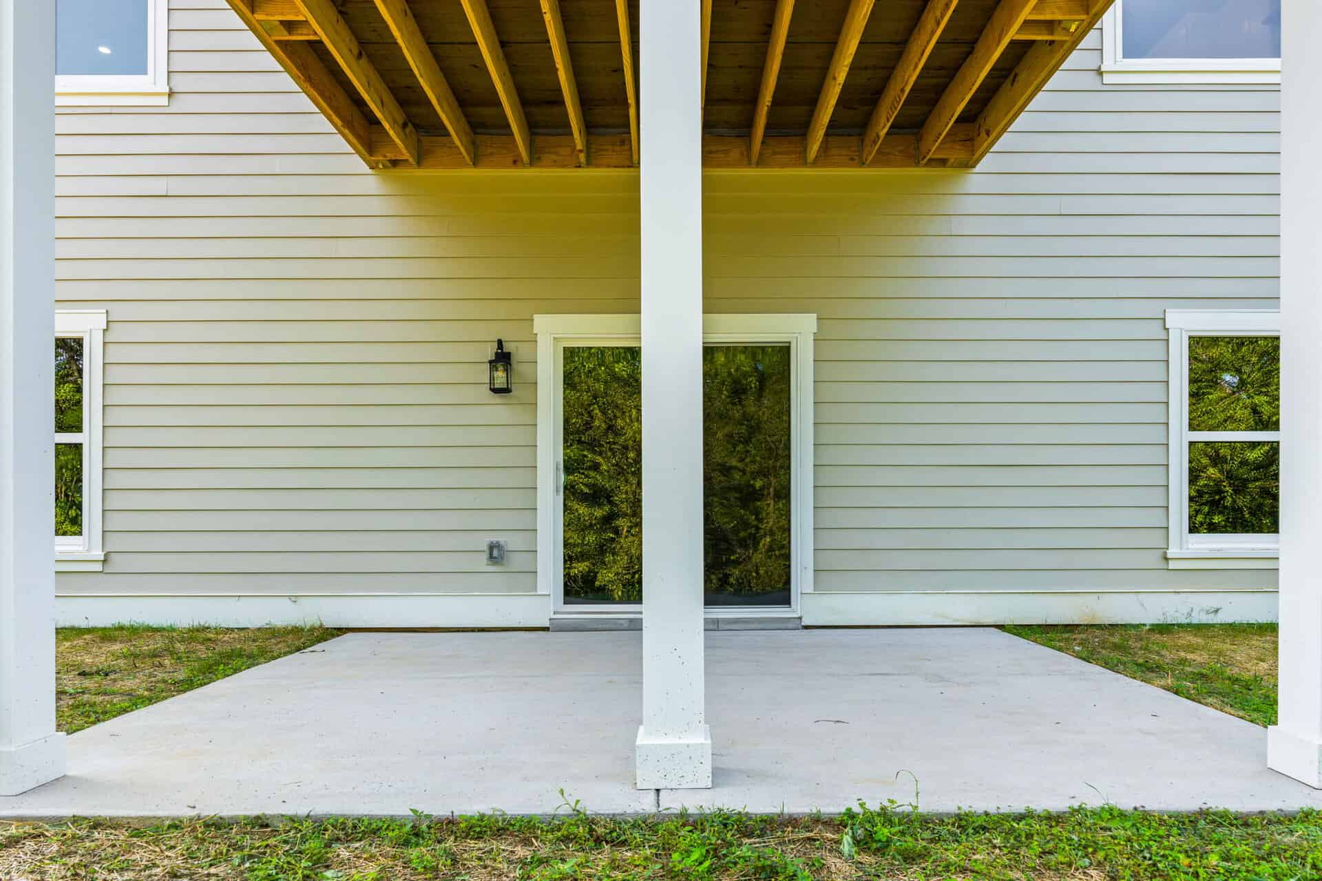 Back porch with sliding glass door and two windows, under a wooden deck.