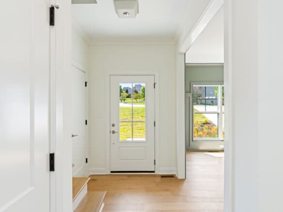 Bright entryway with white walls and natural light from the door and windows.