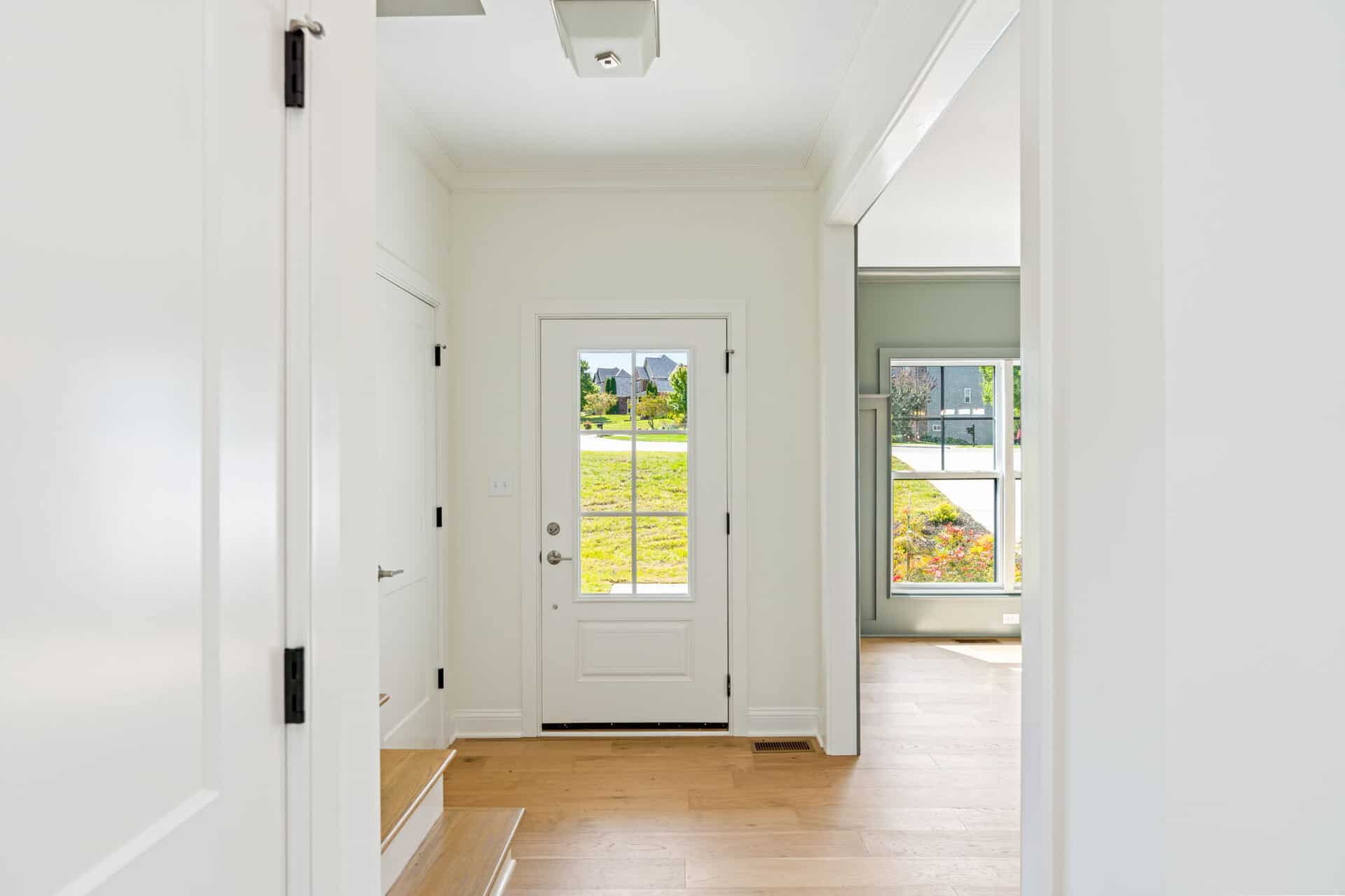 Bright entryway with white walls and natural light from the door and windows.
