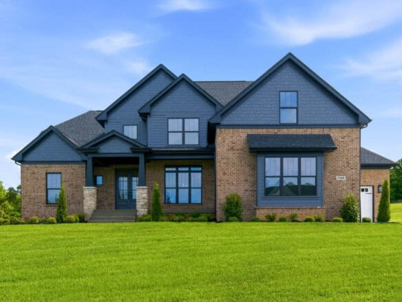 Modern two-story brick and blue siding house with large windows and front lawn.