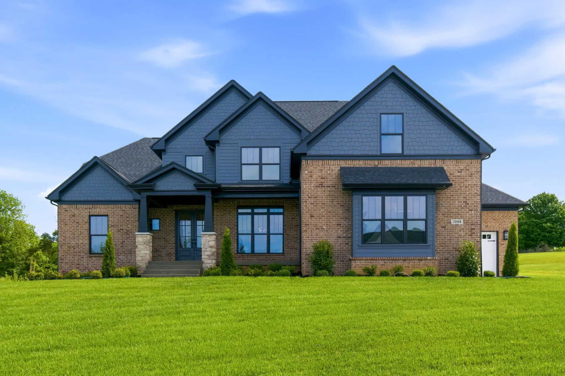 Photography by AS Media Co Modern two-story brick and blue siding house with large windows and front lawn.