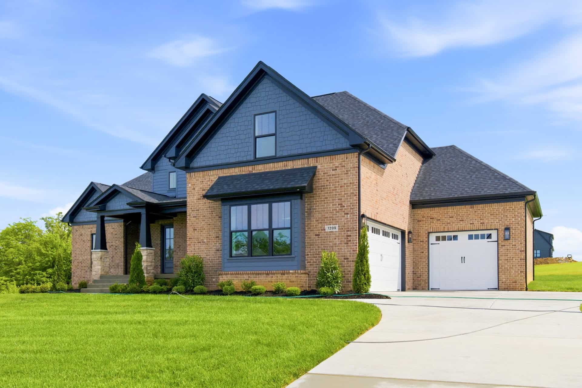 Luxury modern home with brick and blue siding exterior and attached garage.