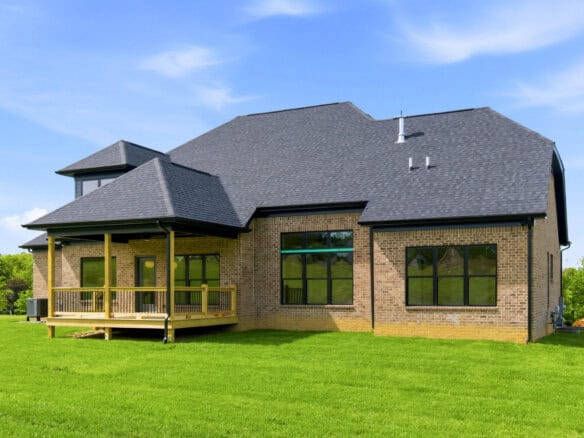 Modern brick home with a spacious wooden deck and green lawn.