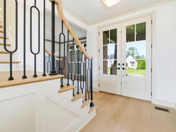 Bright entryway with staircase and glass door leading outside.