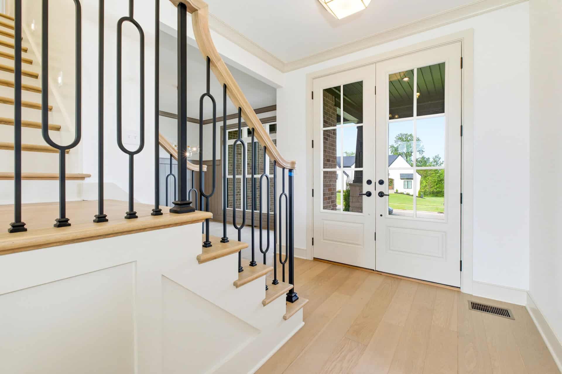 Bright entryway with staircase and glass door leading outside.