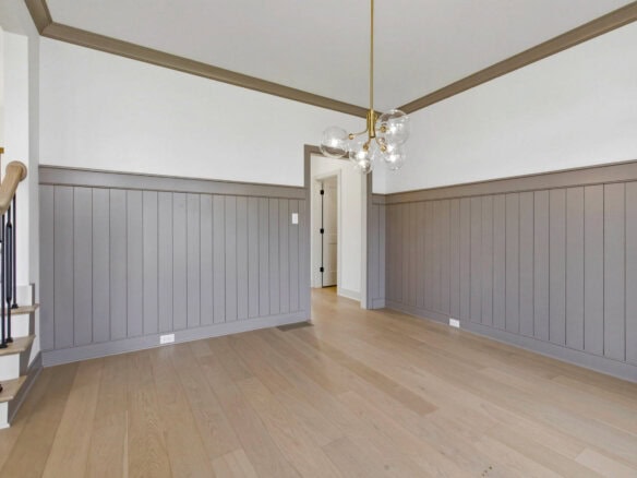 Spacious interior with light wood flooring and gray wainscoting walls.