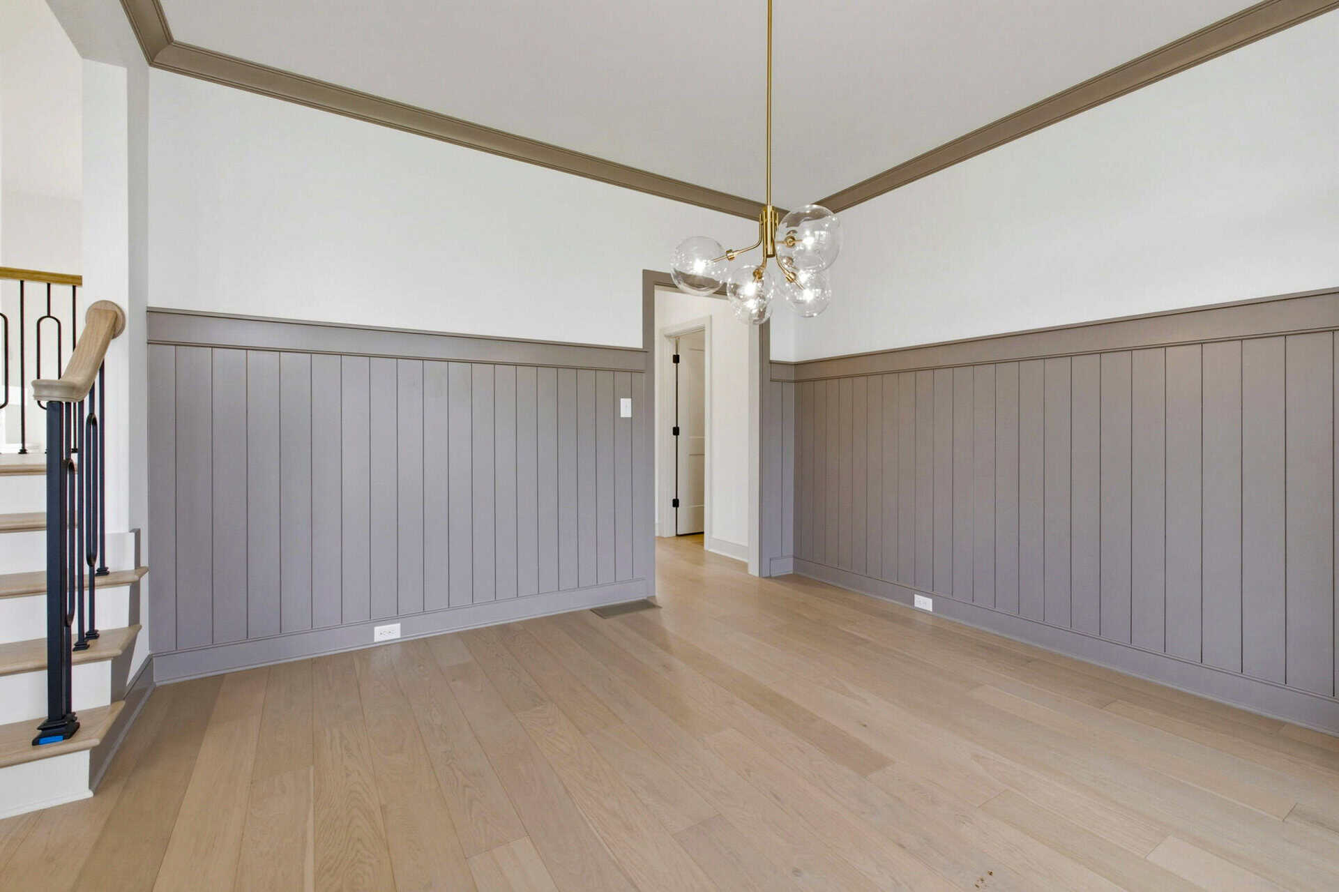Spacious interior with light wood flooring and gray wainscoting walls.