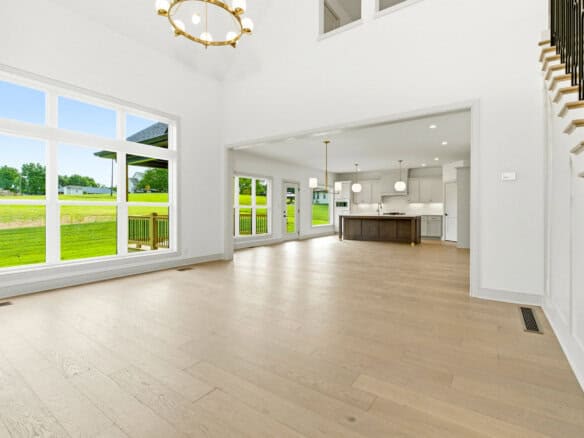 Bright open-concept living area with large window walls, white walls, and a central kitchen island visible in a spacious home interior
