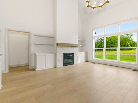 Spacious living room with large window and modern fireplace.