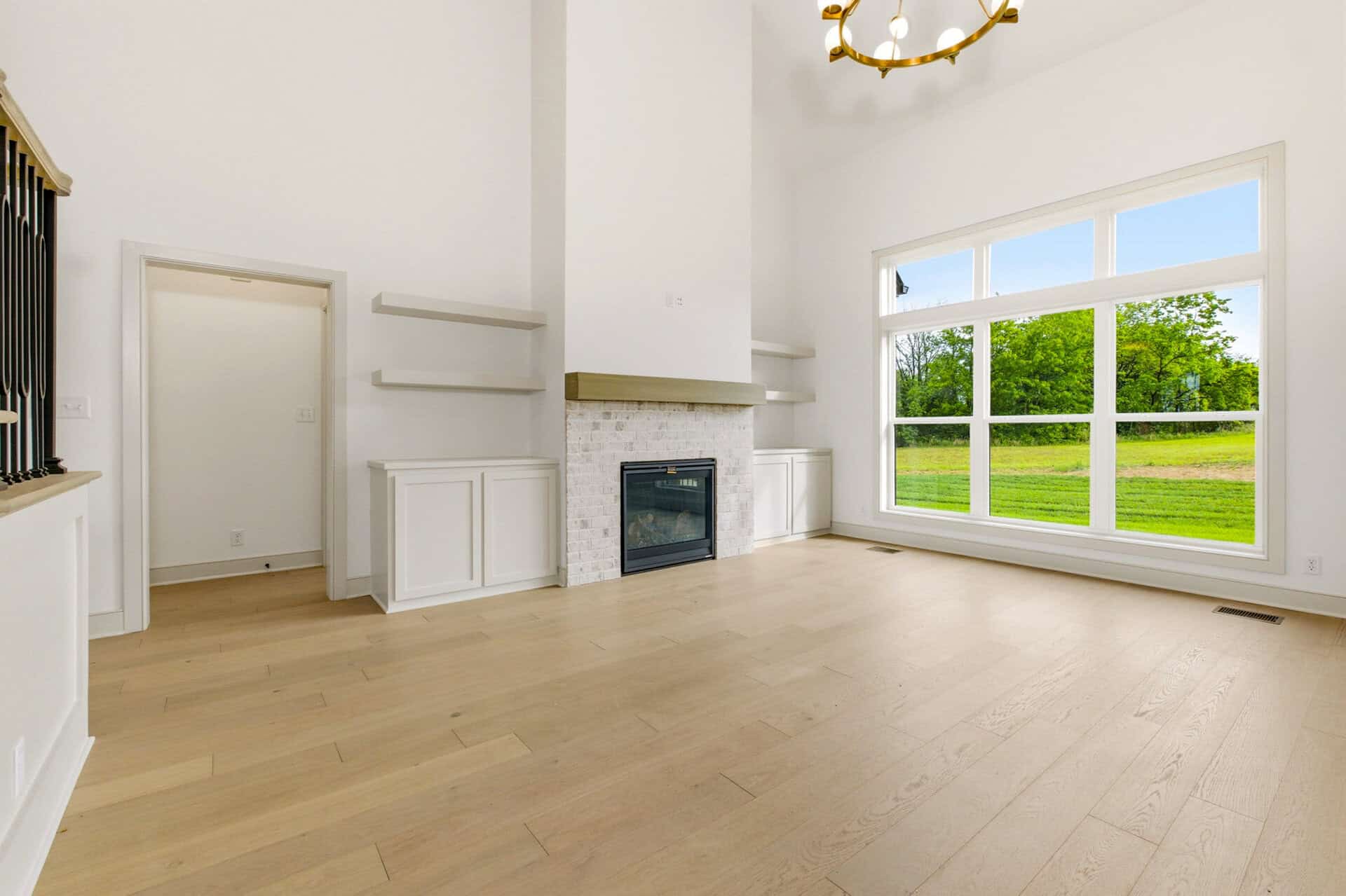 Spacious living room with large window and modern fireplace.