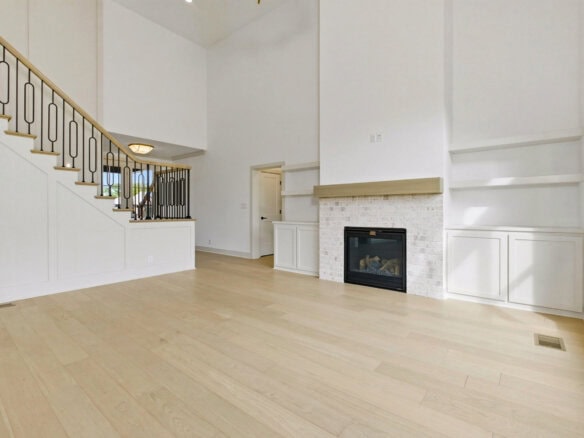 Spacious living room with white walls, fireplace, and large windows.