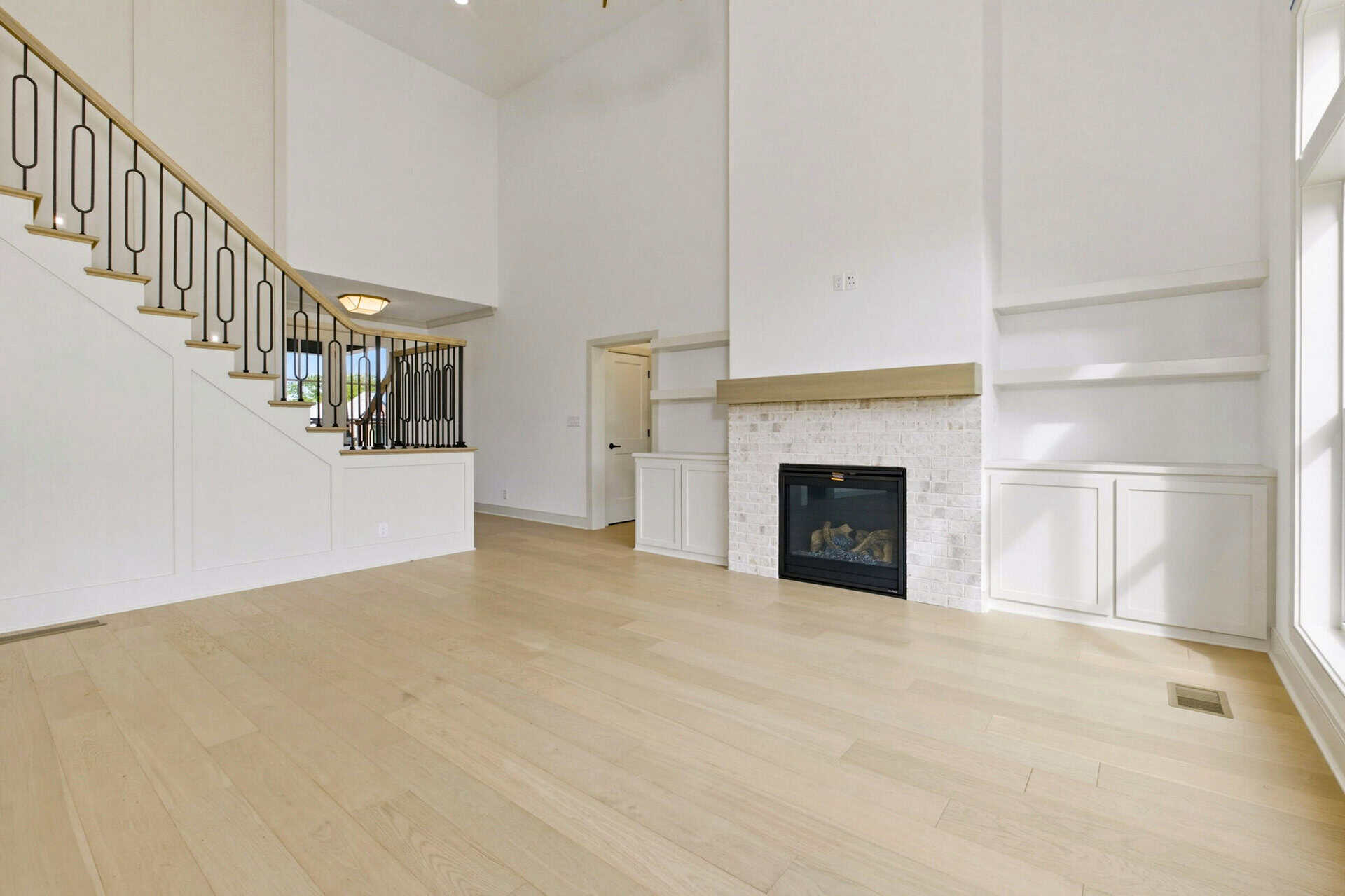 Spacious living room with white walls, fireplace, and large windows.