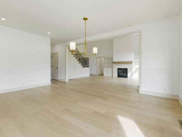 Spacious living room with large windows, hardwood floors, and modern fireplace.