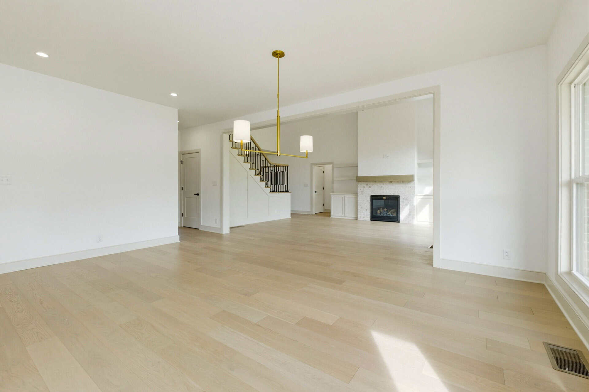 Spacious living room with large windows, hardwood floors, and modern fireplace.