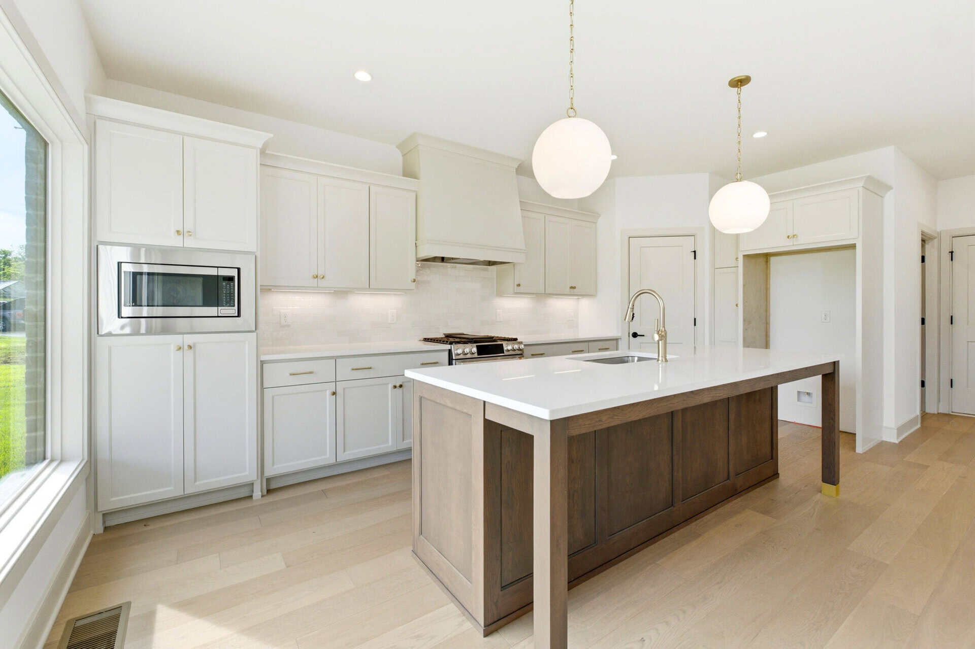 Modern kitchen with white cabinets, island, and pendant lighting.