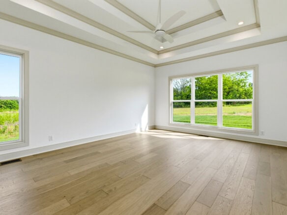 Spacious empty room with large windows and hardwood floors in a new home.