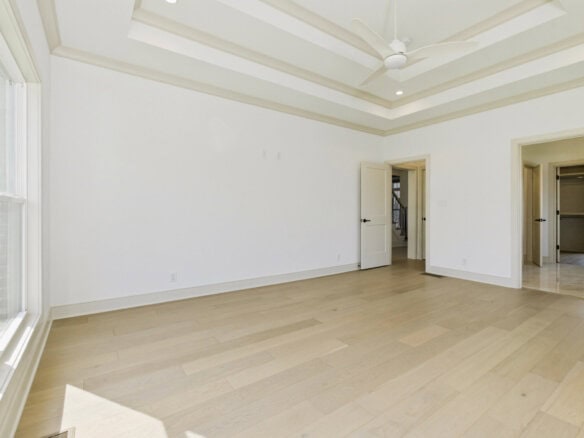 Spacious empty room with large window and high ceiling in a new home.