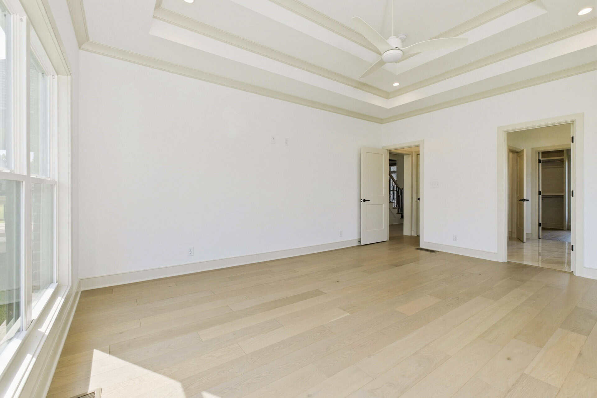 Spacious empty room with large window and high ceiling in a new home.