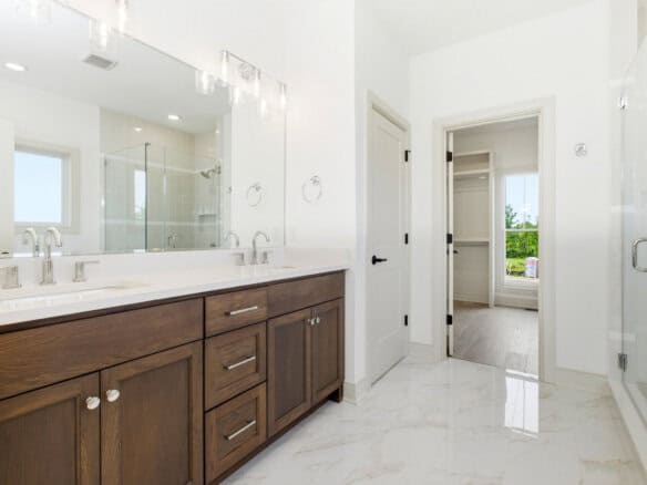 Modern bathroom with double vanity, white walls, and walk-in closet door.