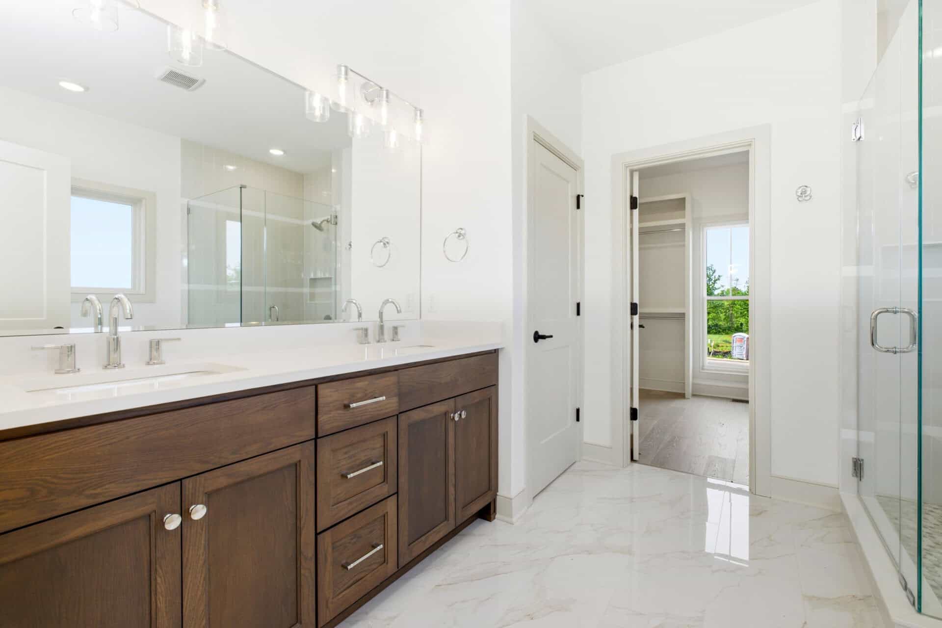 Modern bathroom with double vanity, white walls, and walk-in closet door.