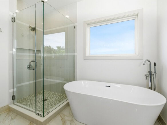 Modern bathroom with glass shower and freestanding bathtub in bright space.