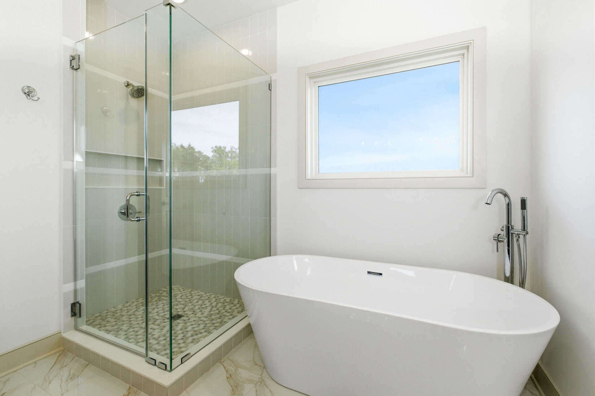 Modern bathroom with glass shower and freestanding bathtub in bright space.